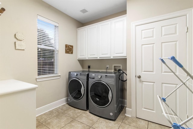 clothes washing area with cabinets, independent washer and dryer, and light tile patterned floors