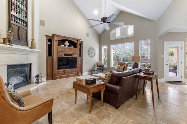 living room featuring a high ceiling, a tile fireplace, and ceiling fan