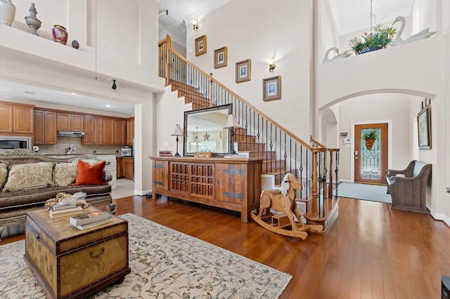 5960HIGHWAY 36 N, Bellville, TX 77418 - living room with arched walkways, baseboards, a high ceiling, stairway, and hardwood / wood-style flooring