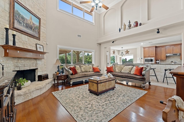 5960HIGHWAY 36 N, Bellville, TX 77418 - living room featuring hardwood / wood-style floors, a high ceiling, a stone fireplace, visible vents, and a ceiling fan