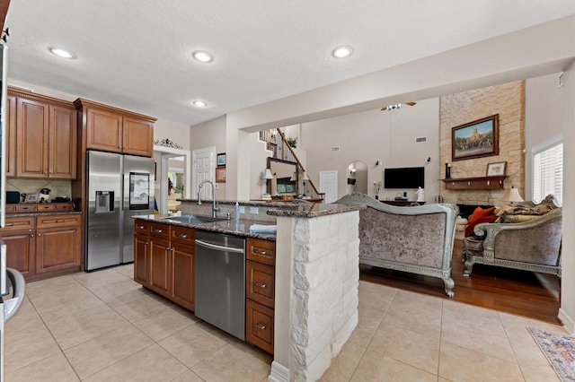 5960HIGHWAY 36 N, Bellville, TX 77418 - kitchen with dark stone counters, a sink, open floor plan, light tile patterned flooring, and stainless steel appliances