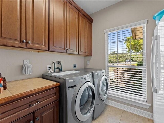 5960HIGHWAY 36 N, Bellville, TX 77418 - laundry area featuring baseboards, independent washer and dryer, light tile patterned floors, and cabinet space