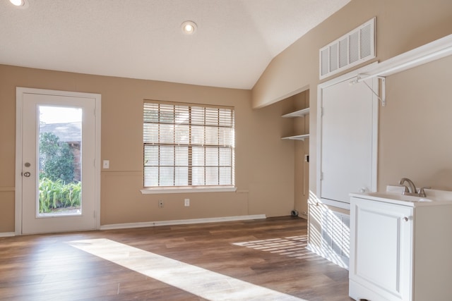 entryway with sink, built in features, hardwood / wood-style floors, a textured ceiling, and vaulted ceiling