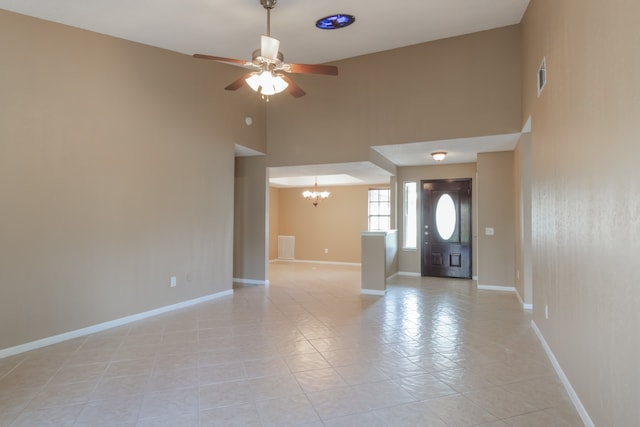 entryway with ceiling fan with notable chandelier and a high ceiling