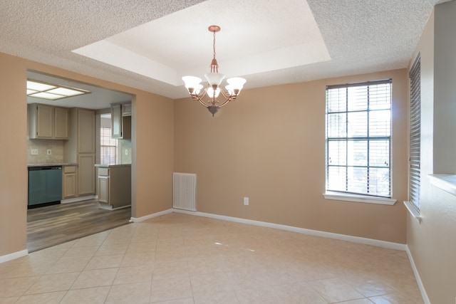 unfurnished dining area with a notable chandelier, a raised ceiling, light tile patterned floors, and a textured ceiling