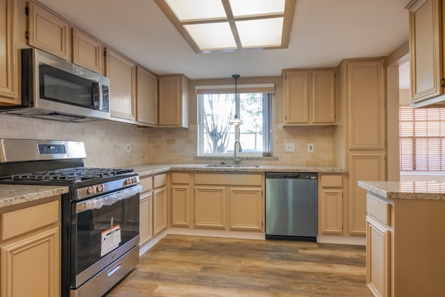 kitchen featuring pendant lighting, light brown cabinets, sink, appliances with stainless steel finishes, and light hardwood / wood-style floors