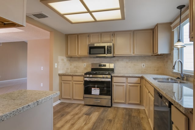 kitchen featuring stainless steel appliances, sink, pendant lighting, light hardwood / wood-style floors, and plenty of natural light