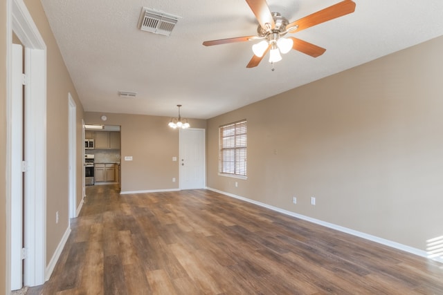 spare room with a textured ceiling, ceiling fan with notable chandelier, and dark hardwood / wood-style floors