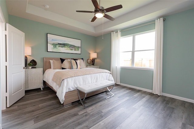 bedroom featuring hardwood / wood-style flooring, ceiling fan, and a tray ceiling