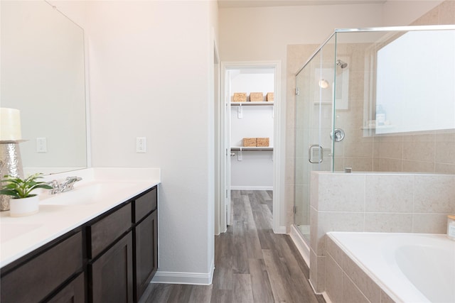 bathroom with hardwood / wood-style flooring, vanity, and plus walk in shower