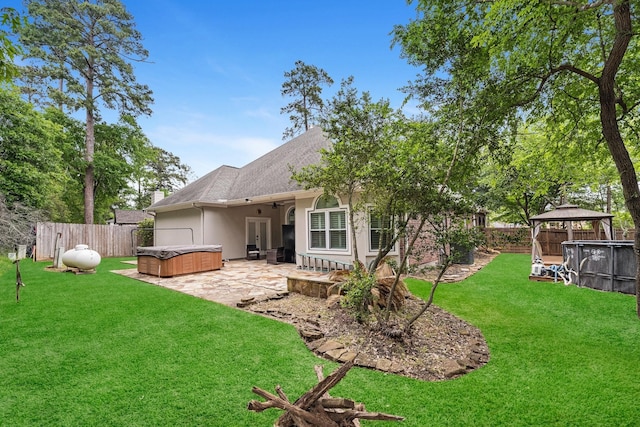 rear view of house with a lawn, a gazebo, ceiling fan, a patio, and a hot tub