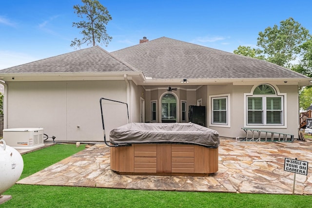 rear view of house with ceiling fan, a patio area, and a hot tub