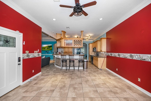 kitchen featuring ceiling fan, light tile patterned flooring, a kitchen bar, and crown molding