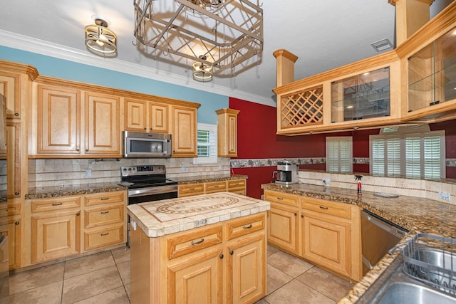 kitchen with a center island, tasteful backsplash, crown molding, light tile patterned flooring, and appliances with stainless steel finishes