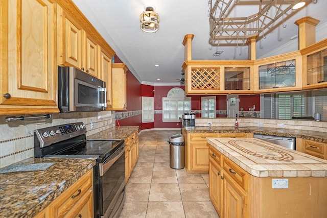 kitchen featuring decorative backsplash, ornamental molding, stainless steel appliances, light tile patterned floors, and a center island