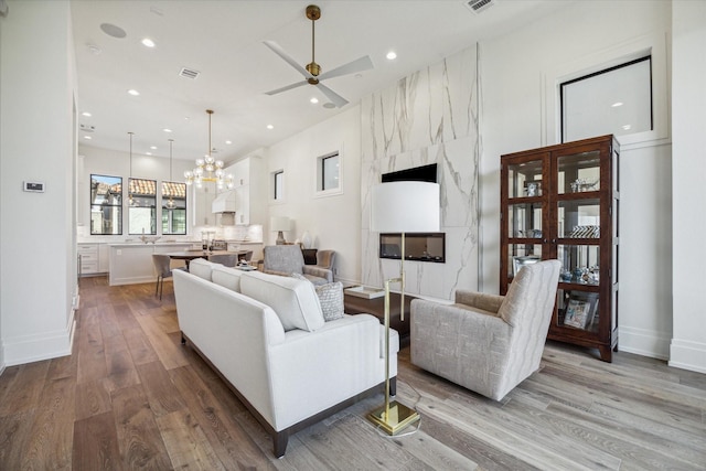 living room featuring wood-type flooring and ceiling fan with notable chandelier