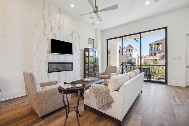 living room with ceiling fan, a fireplace, and wood-type flooring