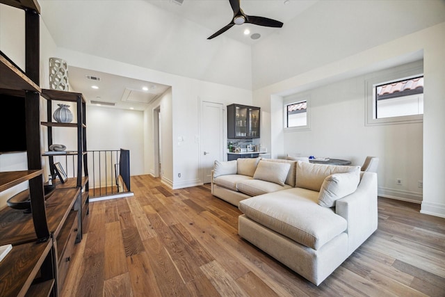 living room featuring ceiling fan, hardwood / wood-style floors, and a towering ceiling