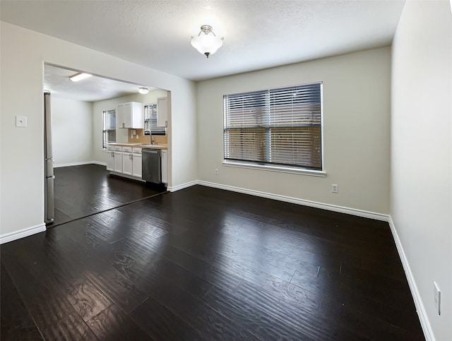 unfurnished living room with a textured ceiling, dark hardwood / wood-style flooring, and sink