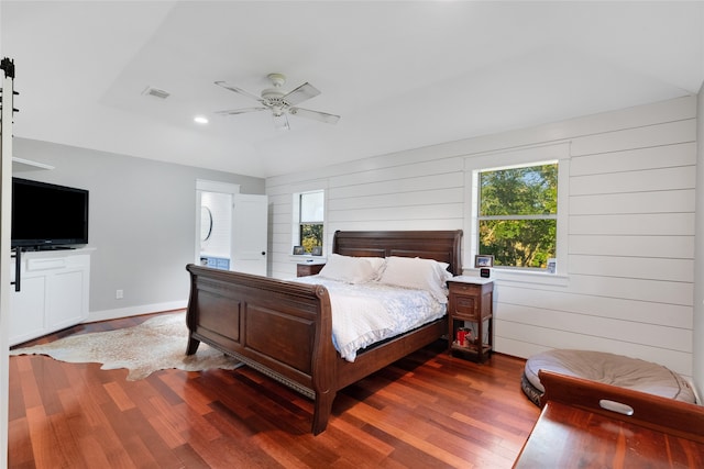 bedroom featuring ceiling fan, wood walls, and hardwood / wood-style flooring