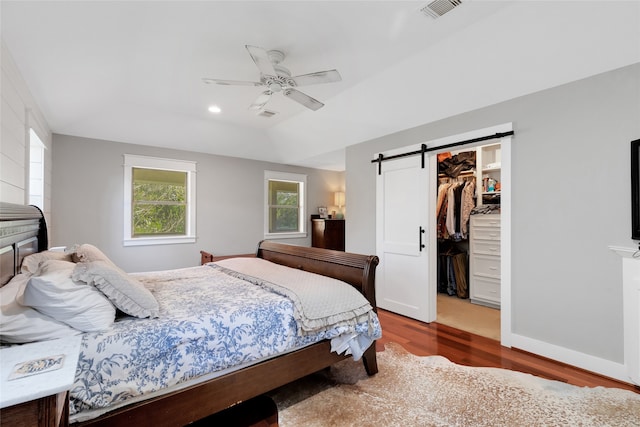 bedroom with hardwood / wood-style floors, ceiling fan, a barn door, a spacious closet, and a closet