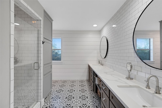 bathroom with wooden walls, plenty of natural light, a shower with shower door, and vanity