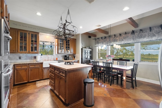 kitchen with beamed ceiling, plenty of natural light, a kitchen island, and decorative backsplash