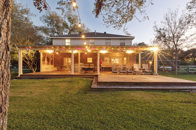 back house at dusk with a lawn and a wooden deck