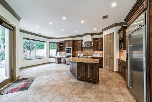 kitchen featuring built in appliances, a kitchen island with sink, a wealth of natural light, and tasteful backsplash