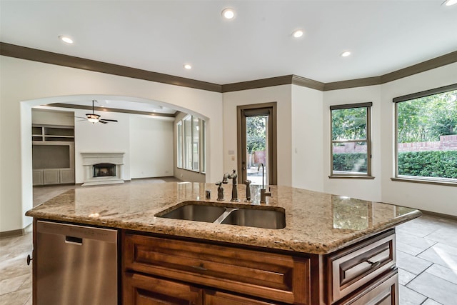 kitchen featuring light stone countertops, ceiling fan, sink, dishwasher, and an island with sink