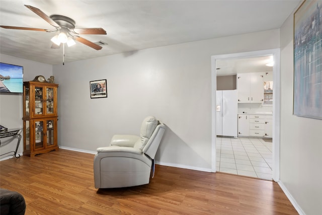 living area with ceiling fan and light hardwood / wood-style flooring