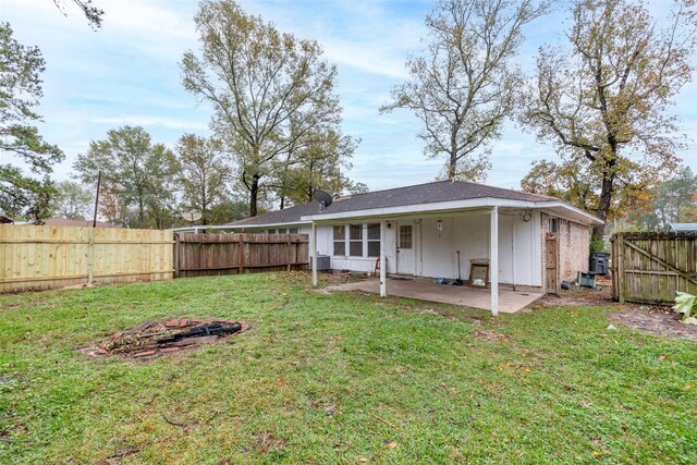 rear view of property with a lawn, a patio area, and an outdoor fire pit