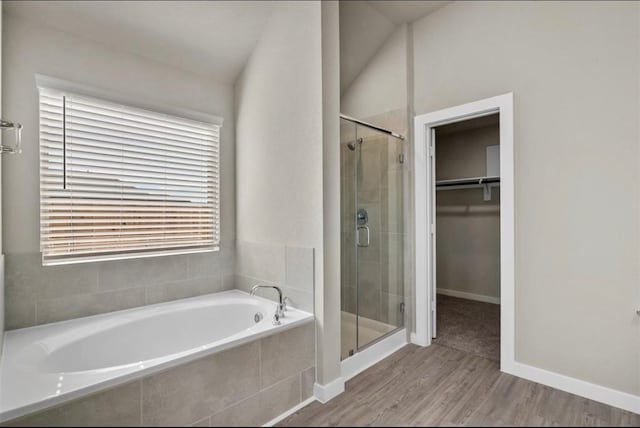 bathroom with wood-type flooring, plus walk in shower, and vaulted ceiling