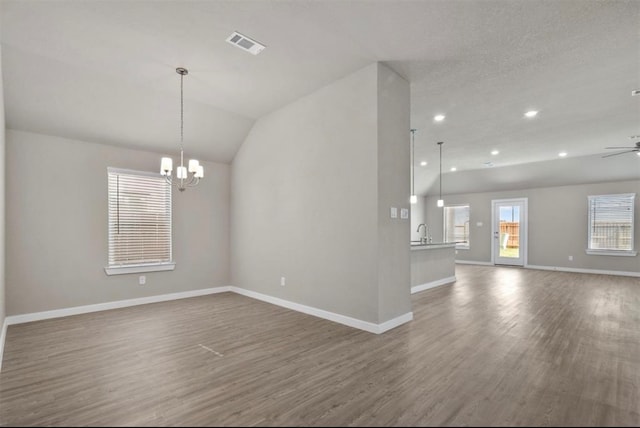 empty room featuring ceiling fan with notable chandelier, dark hardwood / wood-style flooring, lofted ceiling, and sink