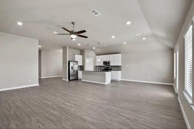 unfurnished living room with hardwood / wood-style floors, vaulted ceiling, plenty of natural light, and ceiling fan