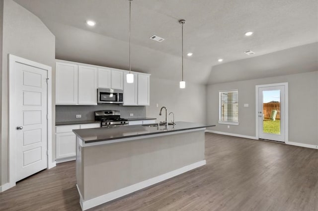 kitchen featuring a kitchen island with sink, hanging light fixtures, sink, vaulted ceiling, and appliances with stainless steel finishes