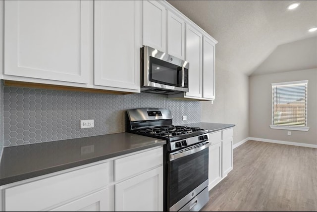 kitchen featuring tasteful backsplash, white cabinetry, stainless steel appliances, and light hardwood / wood-style flooring