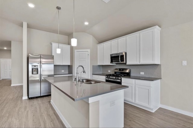 kitchen featuring lofted ceiling, backsplash, sink, appliances with stainless steel finishes, and decorative light fixtures