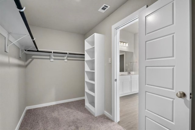 walk in closet featuring light colored carpet