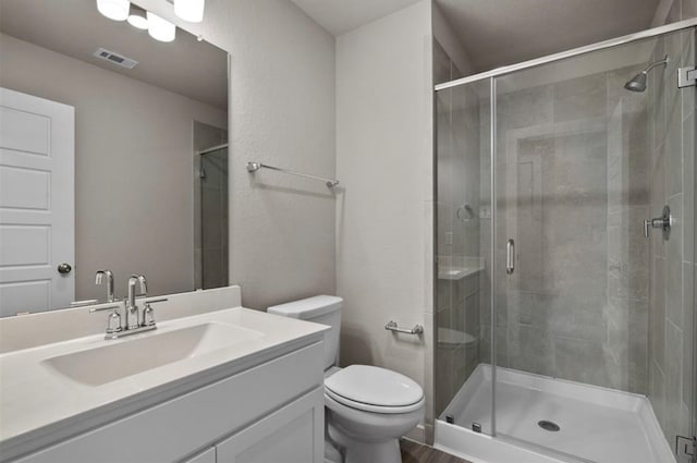 bathroom featuring vanity, a shower with shower door, and toilet