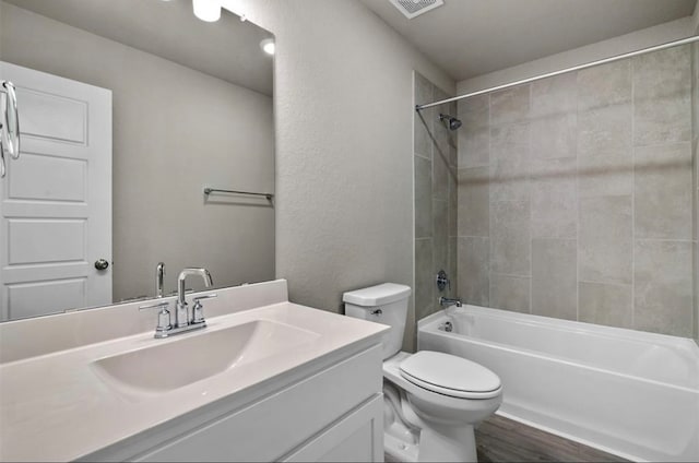 full bathroom with vanity, wood-type flooring, tiled shower / bath combo, and toilet