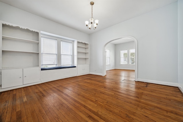 unfurnished living room featuring hardwood / wood-style flooring and an inviting chandelier