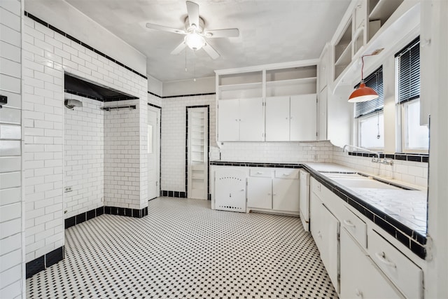 kitchen featuring tasteful backsplash, sink, white cabinets, and hanging light fixtures