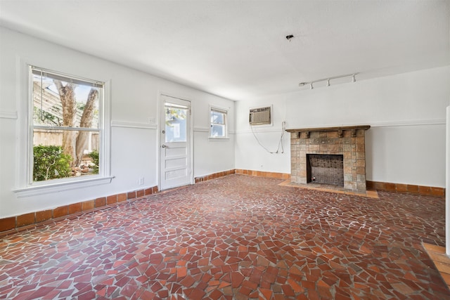 unfurnished living room with plenty of natural light, a wall unit AC, and a tiled fireplace