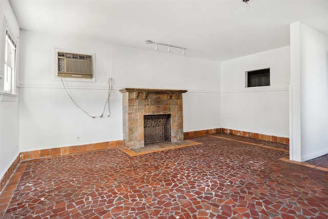 unfurnished living room featuring an AC wall unit, a tile fireplace, and rail lighting