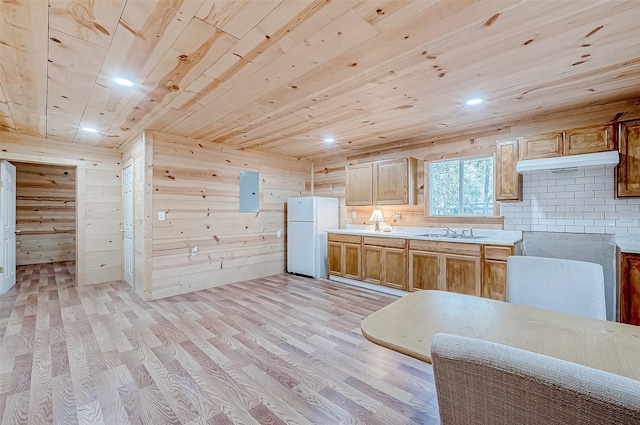 kitchen with light wood-type flooring, sink, wooden ceiling, white fridge, and wood walls