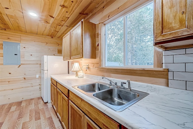 kitchen with wooden walls, sink, electric panel, and light hardwood / wood-style flooring