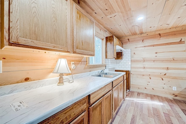 kitchen featuring sink, light stone counters, light hardwood / wood-style flooring, wooden walls, and wood ceiling