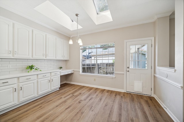 kitchen featuring white cabinetry, backsplash, crown molding, pendant lighting, and light wood-type flooring