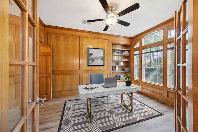 office area with light wood-type flooring, built in features, ornamental molding, and wood walls